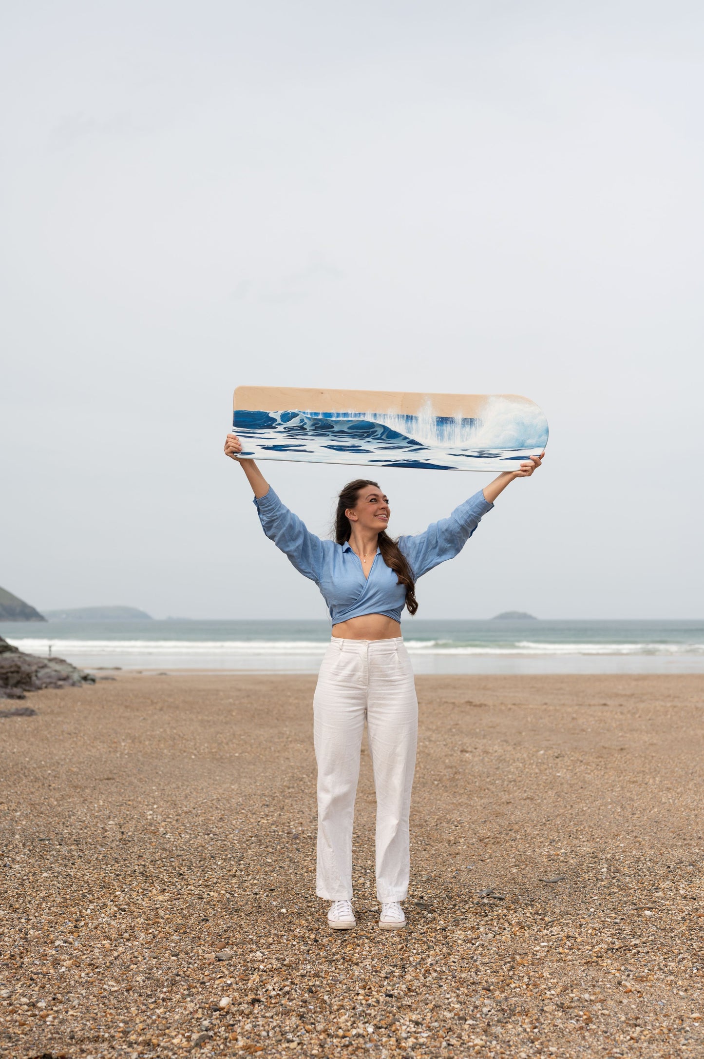 Cornish artist, Phoebe Pocock, at Polzeath with oil painted wooden bellyboard 